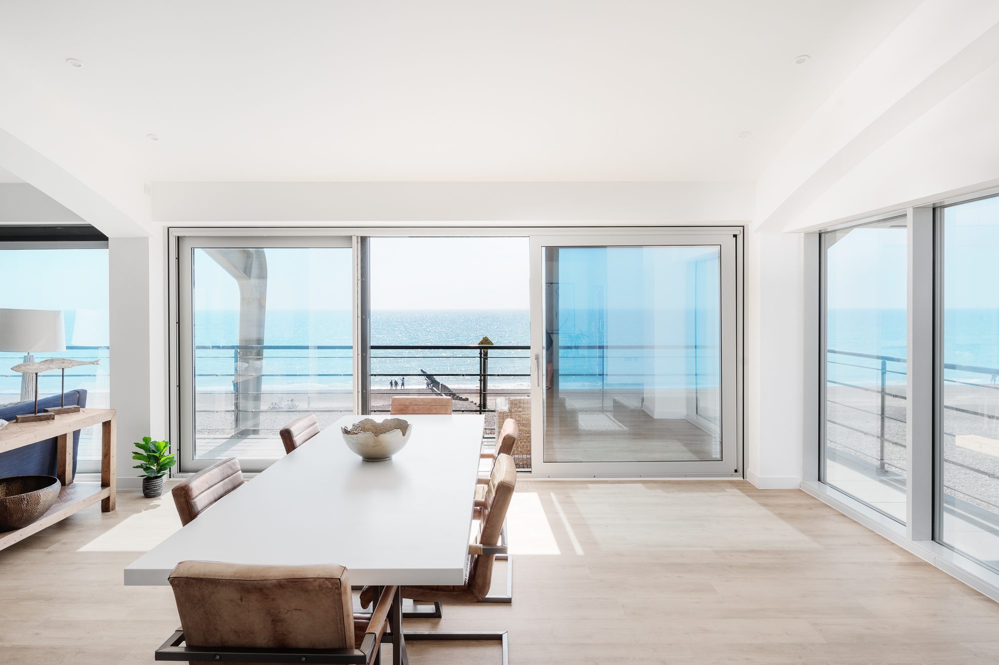 A dining table by the windows of a seafront apartment, with the sea beyond